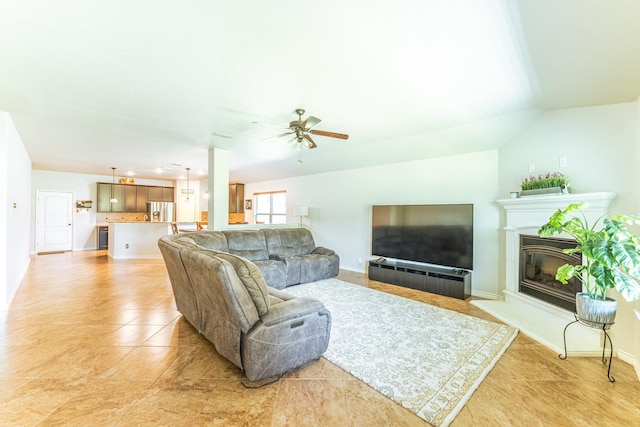 living area with a glass covered fireplace, baseboards, ceiling fan, and light tile patterned floors