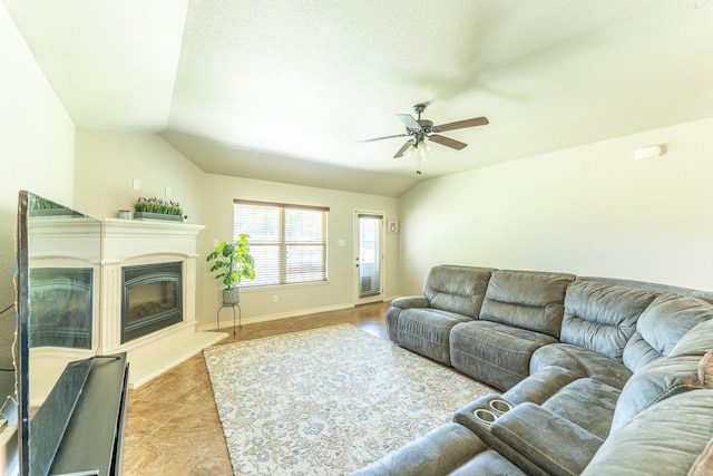 living room featuring a glass covered fireplace, a ceiling fan, and light tile patterned floors