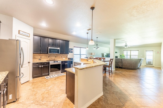kitchen with a wealth of natural light, appliances with stainless steel finishes, open floor plan, and ceiling fan