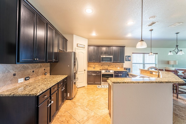 kitchen with stainless steel appliances, a textured ceiling, a sink, visible vents, and decorative backsplash