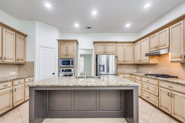 kitchen with a sink, a kitchen island with sink, appliances with stainless steel finishes, under cabinet range hood, and visible vents