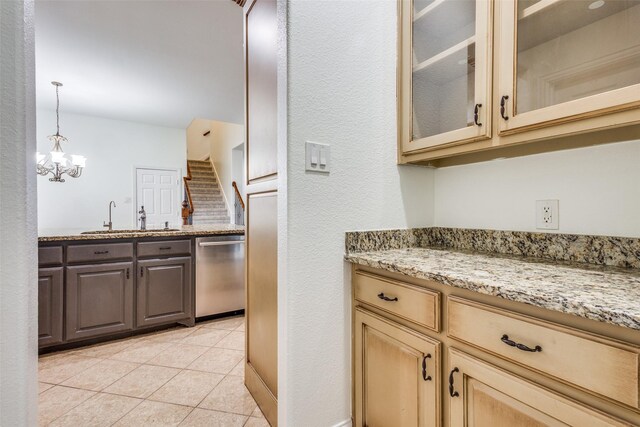 kitchen featuring light stone counters, stainless steel dishwasher, a sink, glass insert cabinets, and a notable chandelier