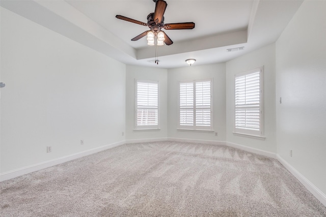 carpeted empty room featuring plenty of natural light, visible vents, and baseboards