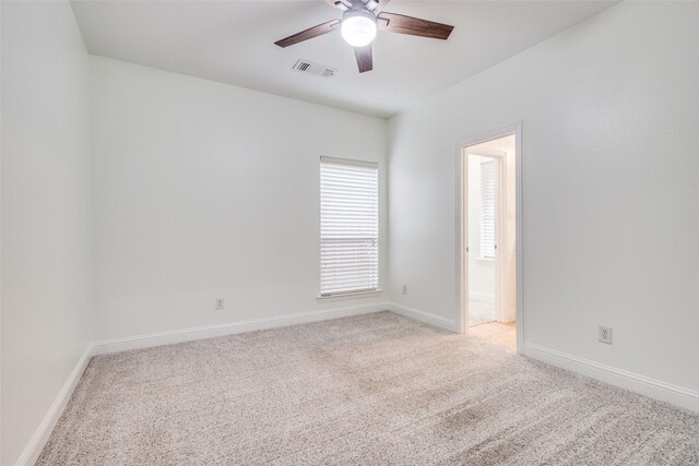 empty room featuring ceiling fan, light carpet, visible vents, and baseboards