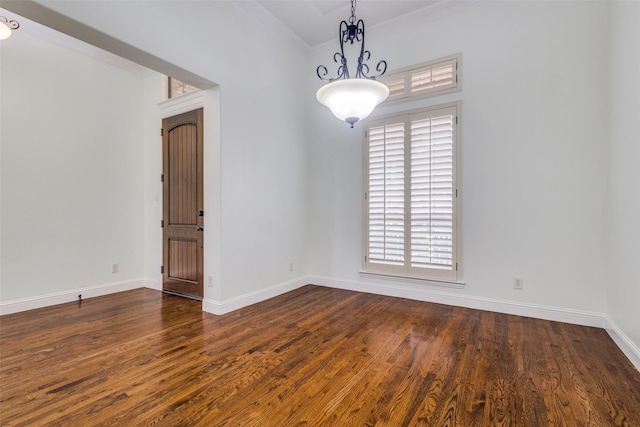empty room featuring baseboards, ornamental molding, and dark wood-style floors