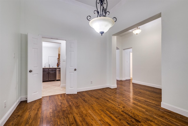 spare room with baseboards, wood finished floors, and ornamental molding