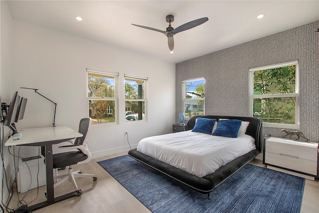 bedroom with recessed lighting, wood finished floors, baseboards, and multiple windows