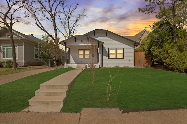 bungalow-style home with a lawn and covered porch