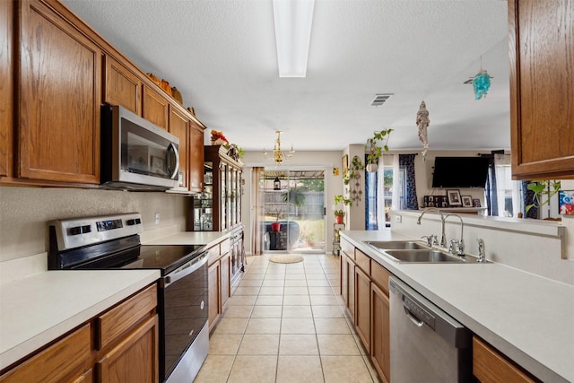 kitchen featuring light countertops, light tile patterned floors, a sink, brown cabinetry, and appliances with stainless steel finishes