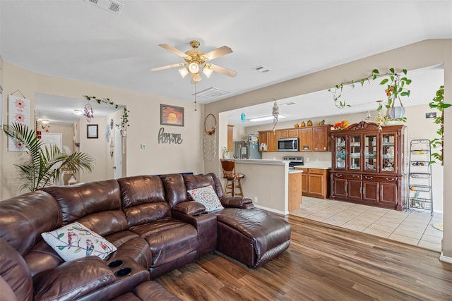living room featuring a ceiling fan, light wood finished floors, and visible vents