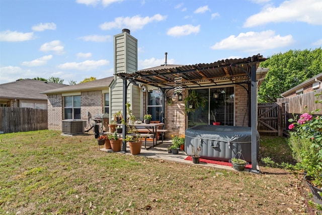 rear view of house with a fenced backyard, a jacuzzi, brick siding, and a patio area