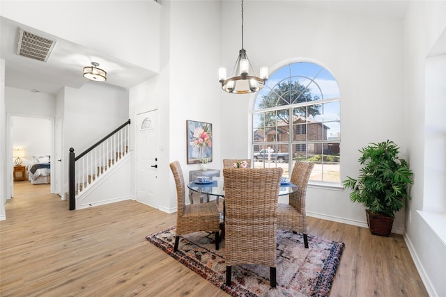 7022 Cottonwood Cir, Sachse, TX 75048 - dining room featuring an inviting chandelier, light wood finished floors, a towering ceiling, and visible vents