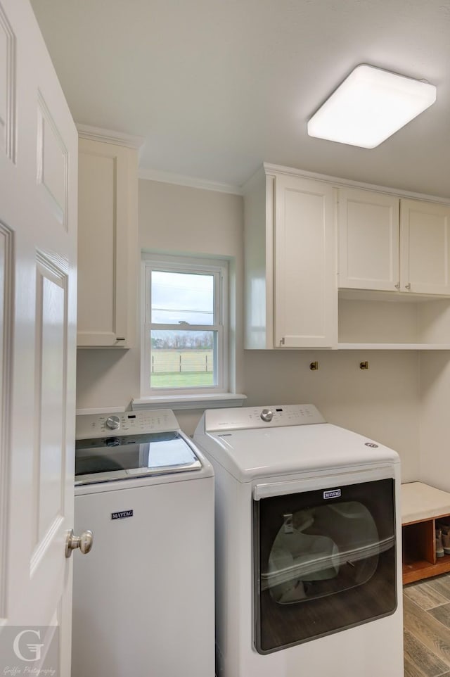 washroom featuring washing machine and clothes dryer, wood finished floors, crown molding, and cabinet space