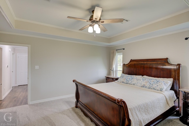 bedroom featuring carpet flooring, a raised ceiling, baseboards, ceiling fan, and ornamental molding