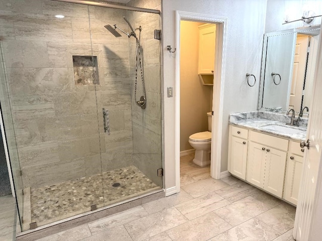 full bath featuring baseboards, vanity, toilet, and a stall shower