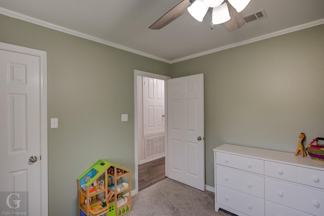 recreation room featuring carpet flooring, baseboards, visible vents, a ceiling fan, and crown molding
