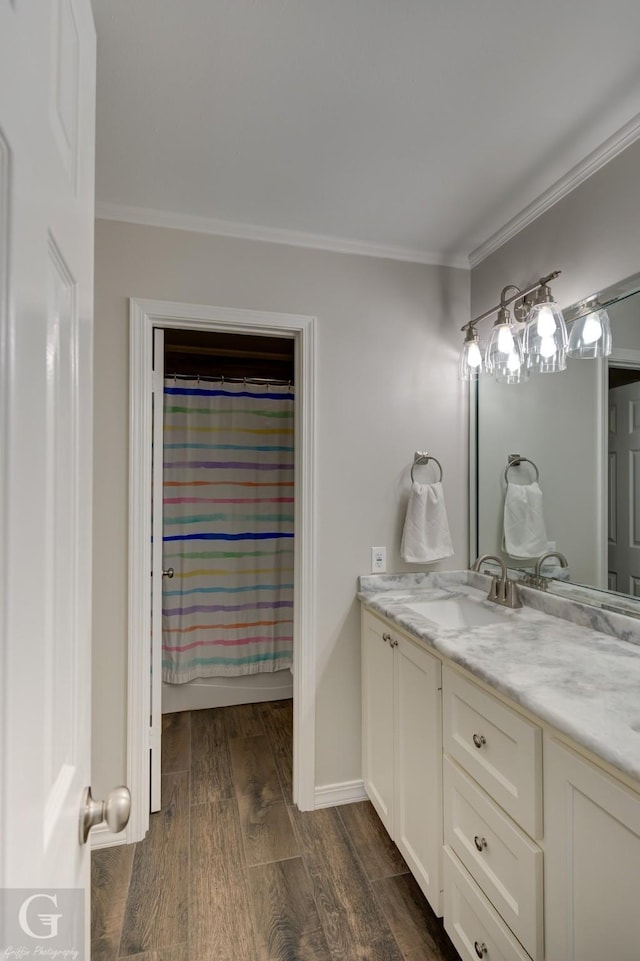 full bath with double vanity, wood finished floors, crown molding, and a sink