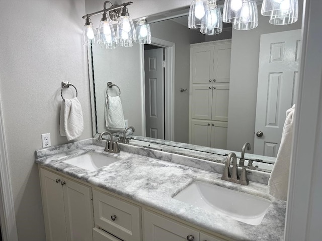 full bath with a sink, a notable chandelier, and double vanity