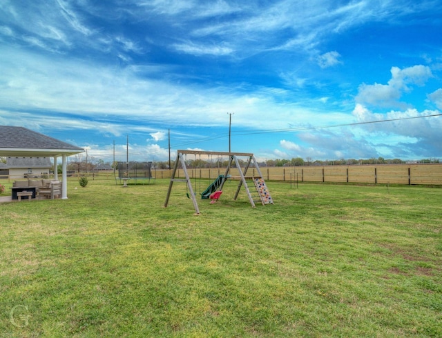 view of playground featuring a trampoline, a lawn, and a fenced backyard