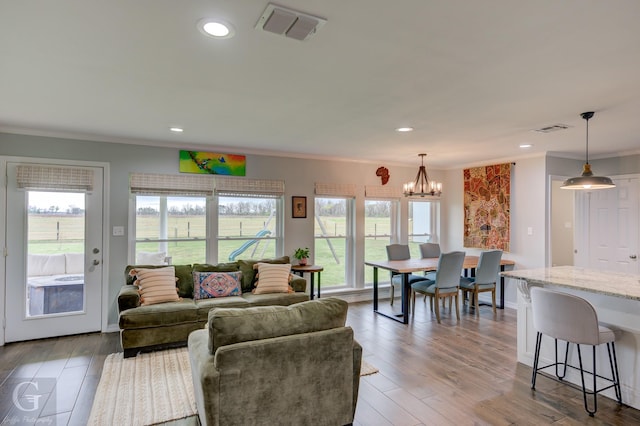 living room featuring a notable chandelier, visible vents, ornamental molding, and a healthy amount of sunlight