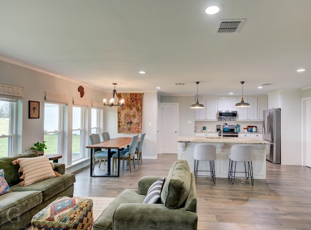 living room with an inviting chandelier, ornamental molding, visible vents, and recessed lighting