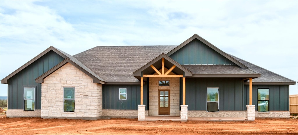 view of front of property with board and batten siding, a shingled roof, and stone siding