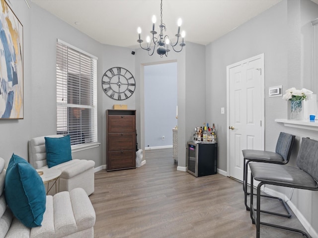 living area featuring baseboards, light wood finished floors, and a notable chandelier