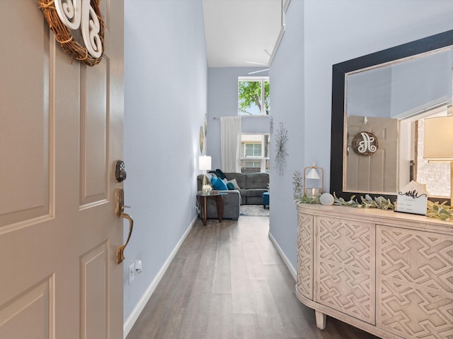 foyer entrance with baseboards, wood finished floors, and vaulted ceiling
