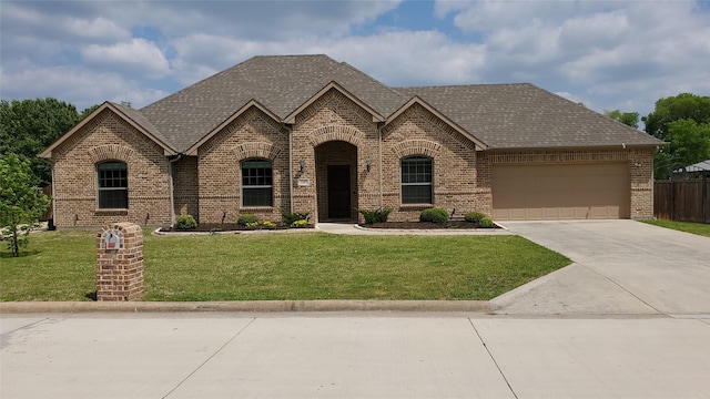 french country home featuring brick siding, an attached garage, driveway, and roof with shingles