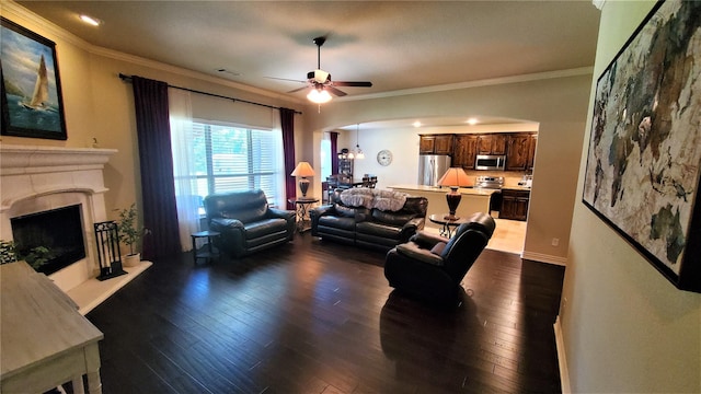 living area featuring arched walkways, crown molding, and dark wood-style floors