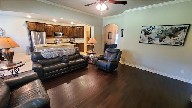 living room with a ceiling fan, wood finished floors, arched walkways, baseboards, and ornamental molding