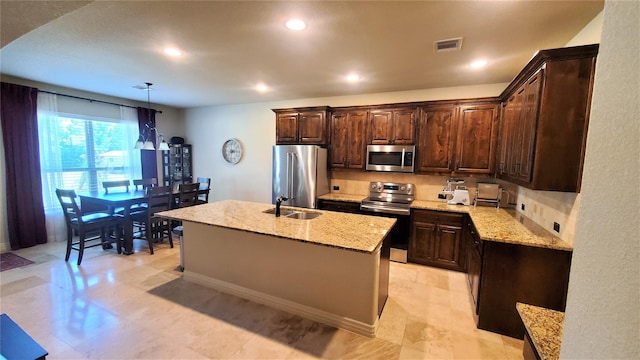 kitchen featuring stainless steel appliances, a sink, dark brown cabinets, visible vents, and light stone countertops