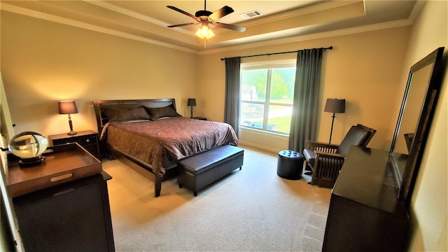 carpeted bedroom featuring baseboards, visible vents, a raised ceiling, and crown molding