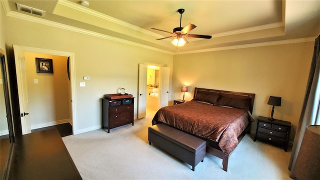 bedroom with light carpet, visible vents, crown molding, connected bathroom, and a raised ceiling