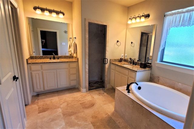 full bath featuring two vanities, a garden tub, a sink, and a stall shower