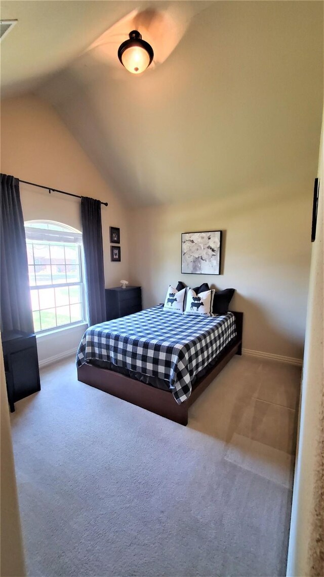 carpeted bedroom featuring lofted ceiling and baseboards