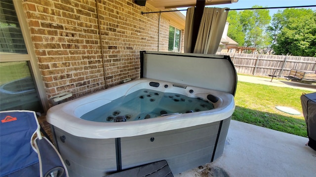 exterior details featuring brick siding, a jacuzzi, and fence