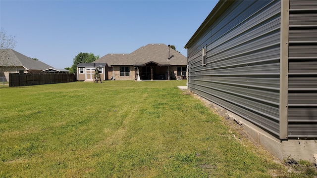 view of yard with an outdoor structure, fence, and a storage shed