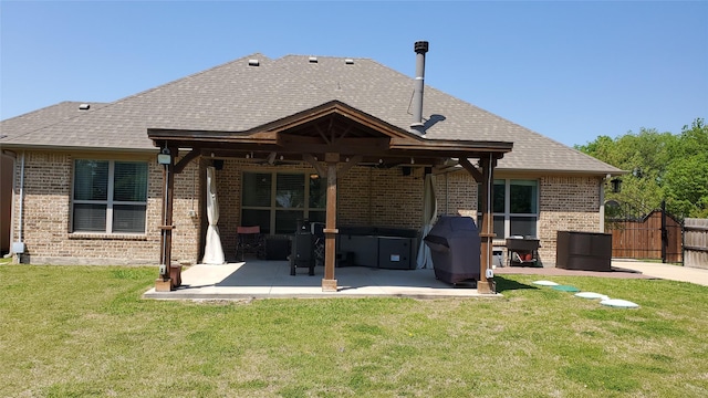 back of property with brick siding, a patio area, fence, a yard, and roof with shingles