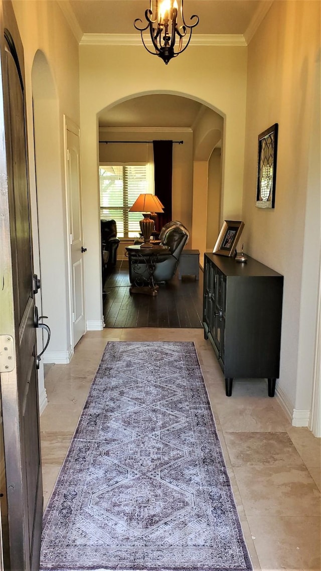 entrance foyer with an inviting chandelier, arched walkways, and crown molding