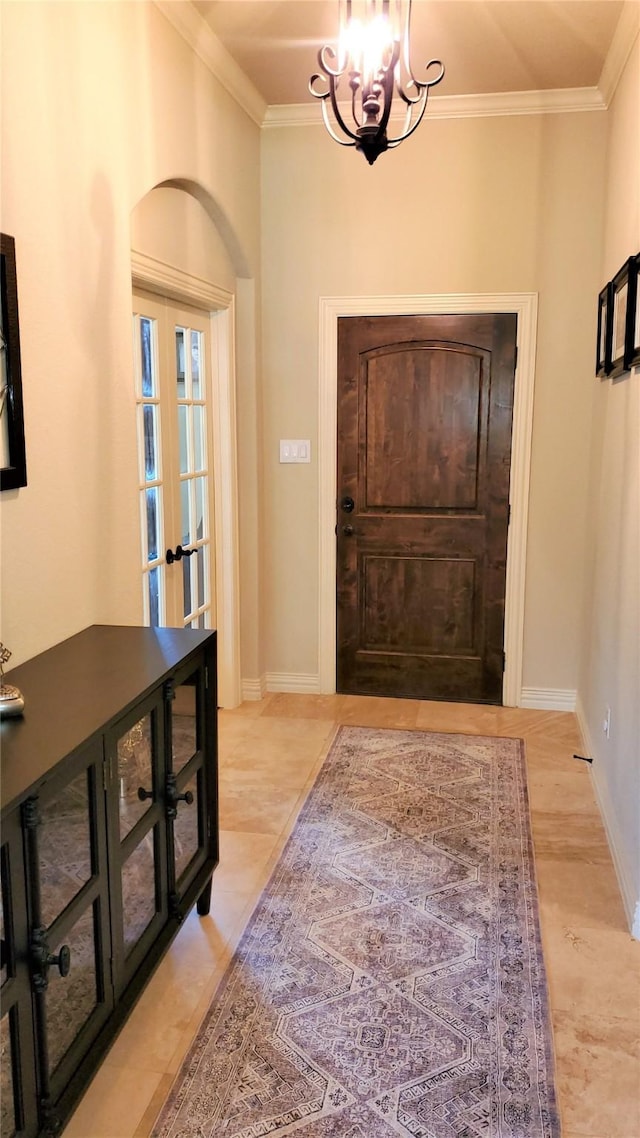foyer featuring an inviting chandelier, crown molding, french doors, and baseboards