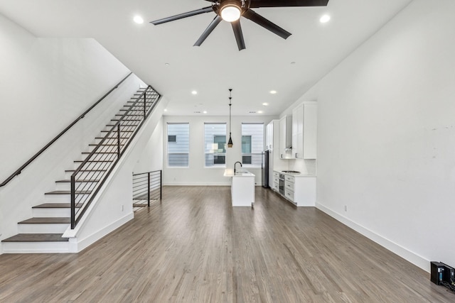 2912 Raleigh St Unit 102, Dallas, TX 75219 - unfurnished living room with a ceiling fan, baseboards, stairs, and dark wood-type flooring