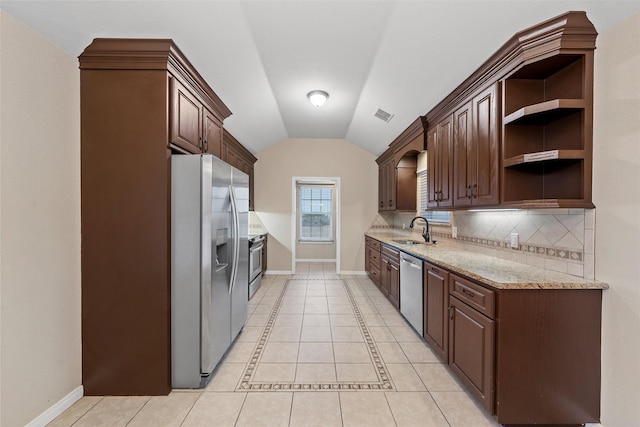 kitchen featuring vaulted ceiling, appliances with stainless steel finishes, baseboards, and a sink