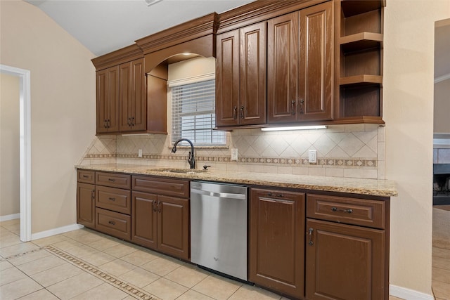 kitchen featuring decorative backsplash, stainless steel dishwasher, a sink, and vaulted ceiling
