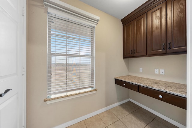 unfurnished office featuring built in study area, baseboards, and light tile patterned flooring