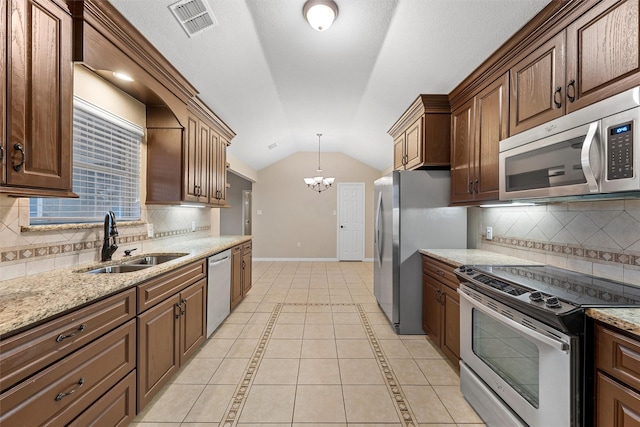 kitchen with lofted ceiling, stainless steel appliances, a sink, baseboards, and a notable chandelier