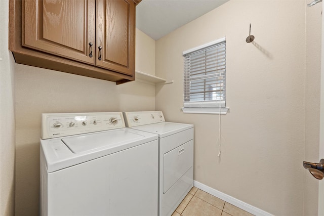 laundry room featuring washing machine and clothes dryer, cabinet space, light tile patterned flooring, and baseboards