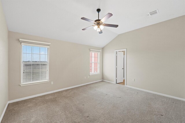 carpeted empty room with a wealth of natural light, a ceiling fan, visible vents, and baseboards