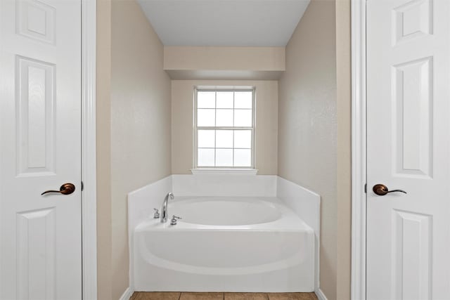 bathroom with a textured wall and a garden tub