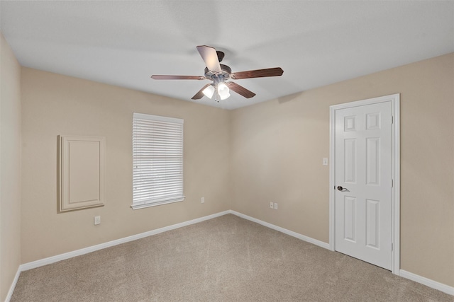 spare room with carpet floors, a ceiling fan, and baseboards